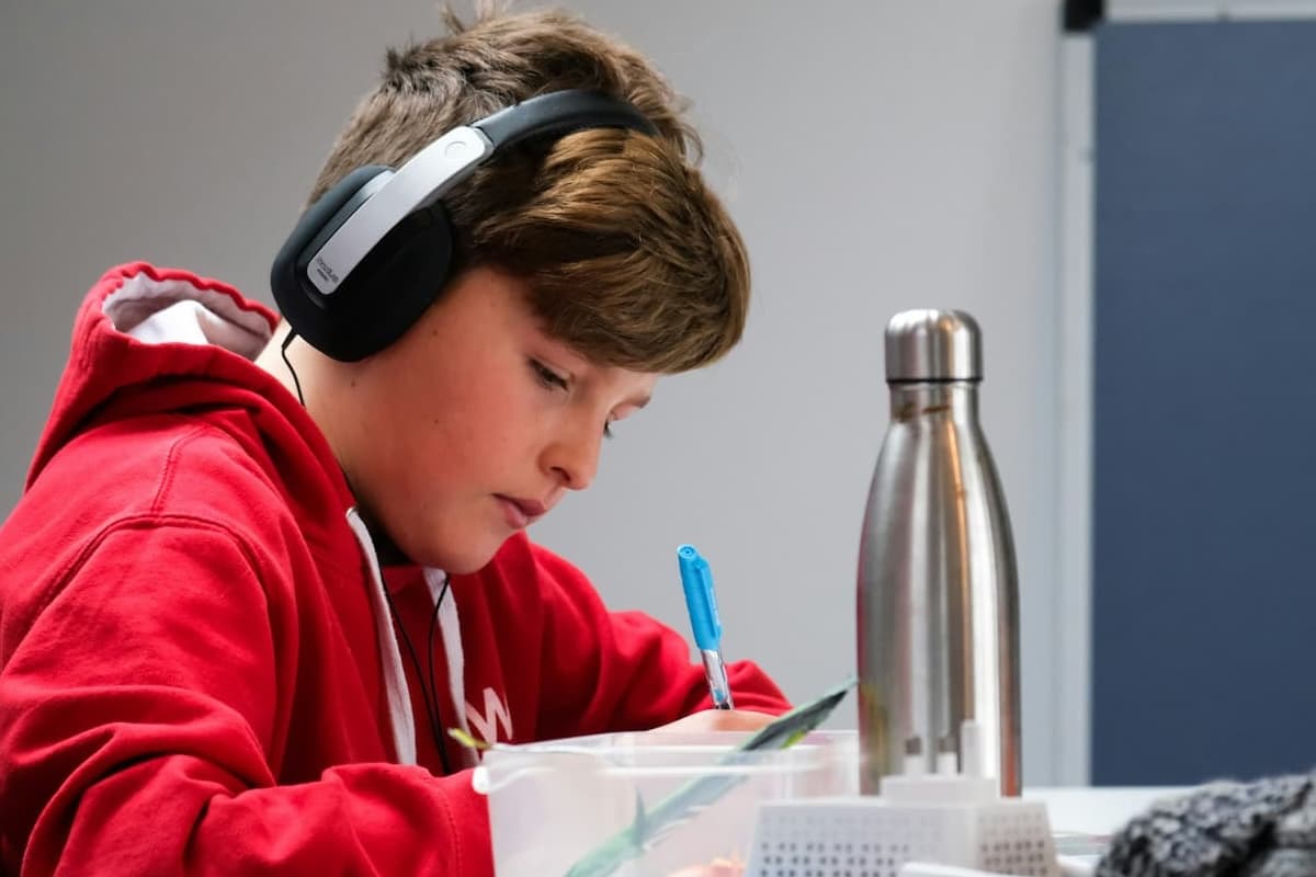 A child wearing headphones, focused and working at a desk