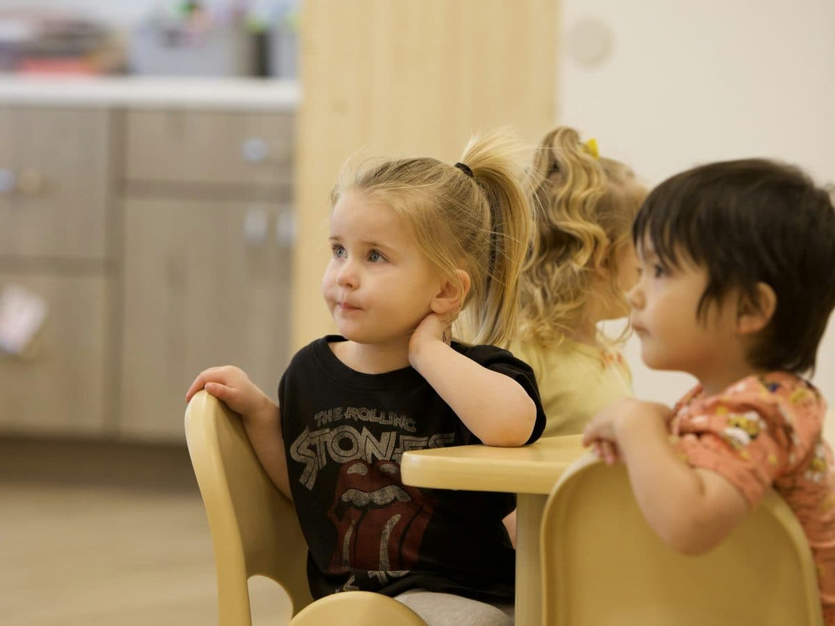 Young children sitting at a low table in a nursery room