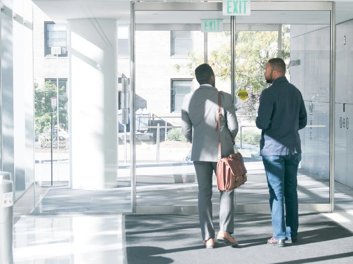 Two colleagues standing talking in a bright, glazed entrance hall