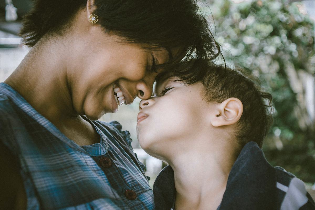 A parent and their child resting their foreheads together, laughing